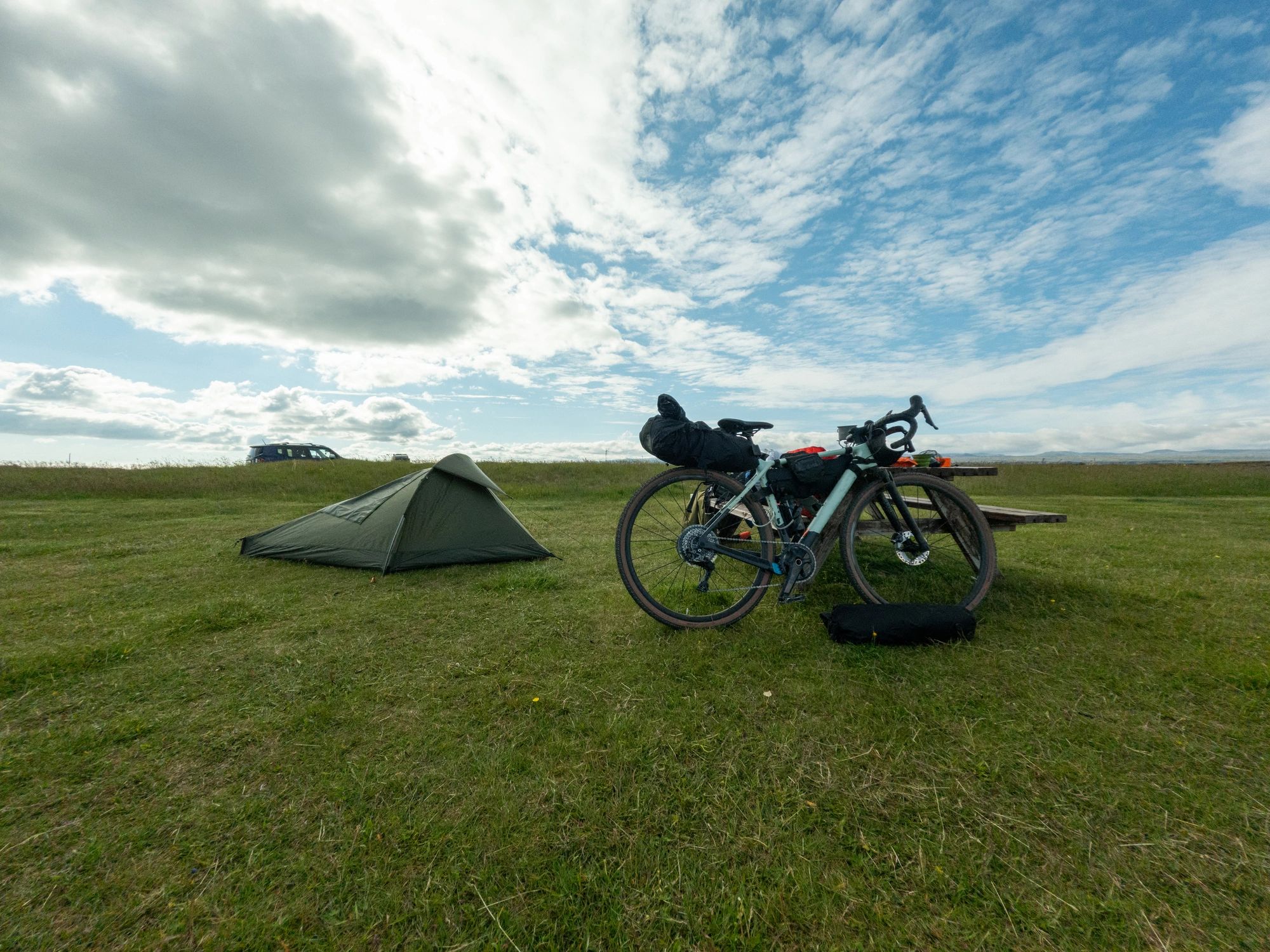 Outdoor campsite with tent and gear in an open field