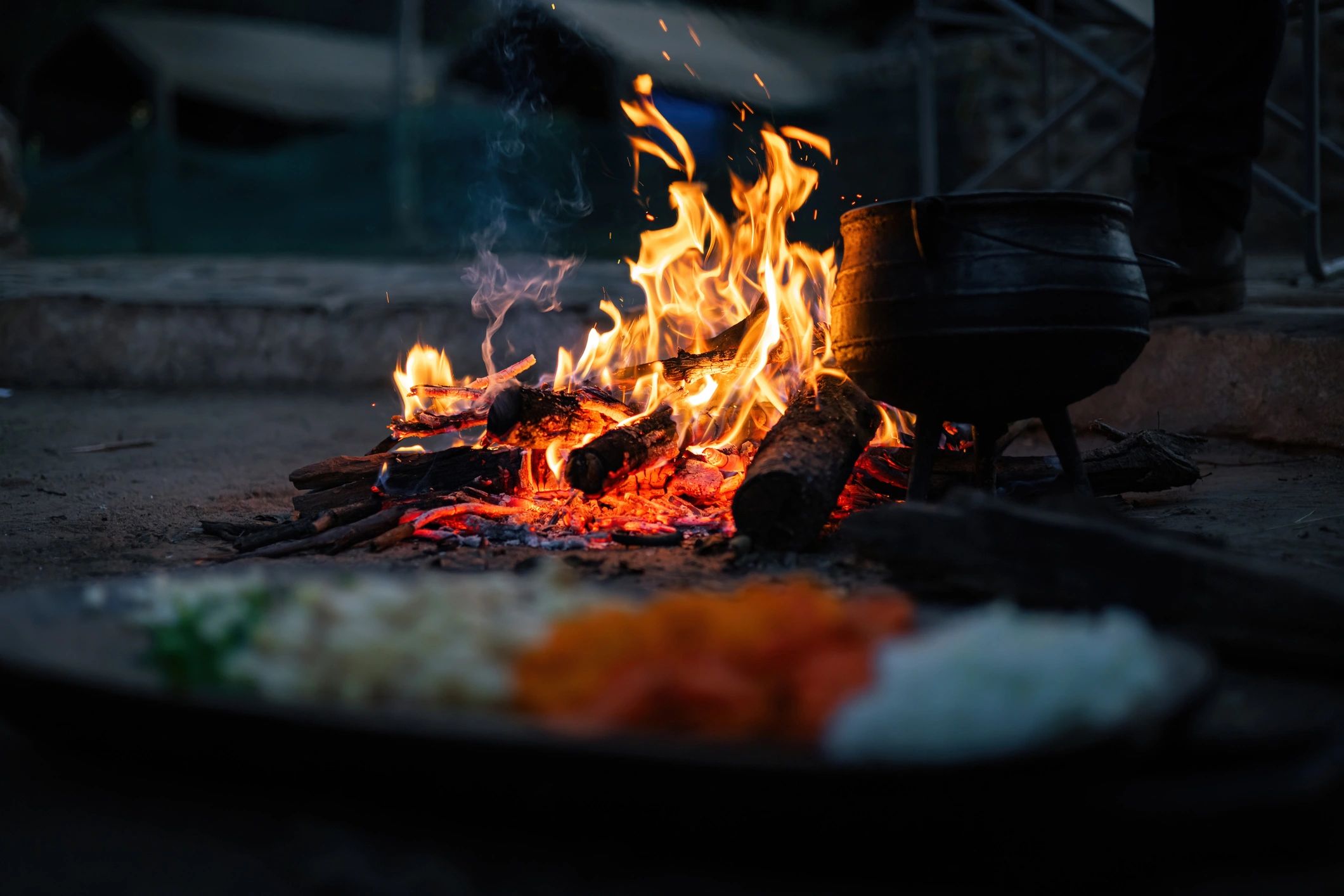Outdoor campfire cooking setup with pot and prepared ingredients